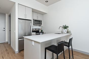 A kitchen with a white countertop and black chairs.